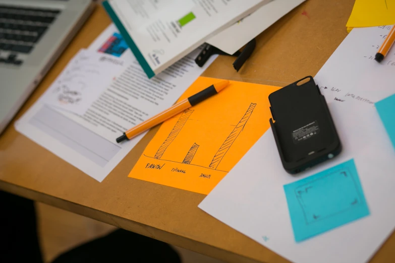 notepad and notebook on desk covered in papers