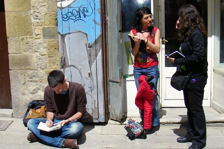 two young women sitting and standing near two men writing