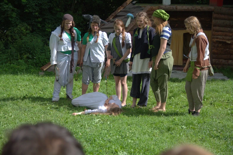 a group of people standing around a body on the grass
