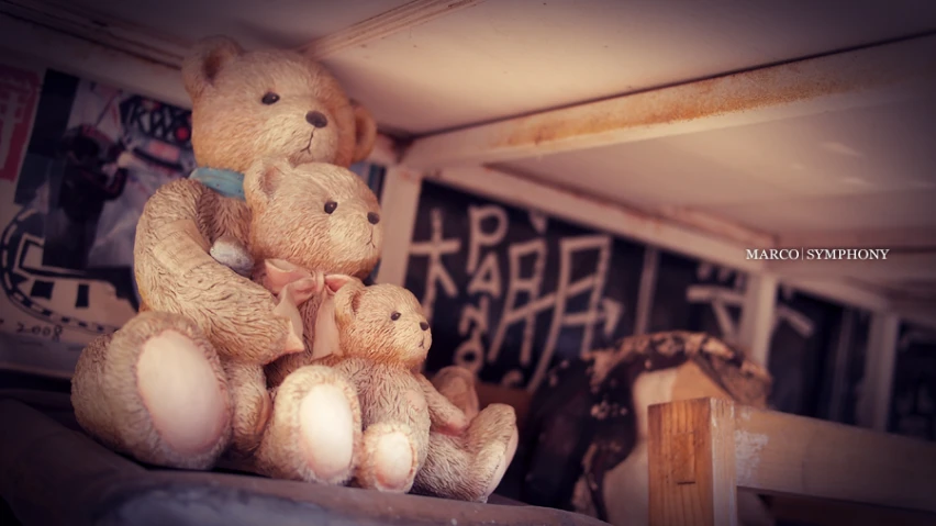 some brown teddy bears in front of some wall graffiti