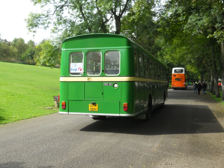 green and orange buses driving down the street