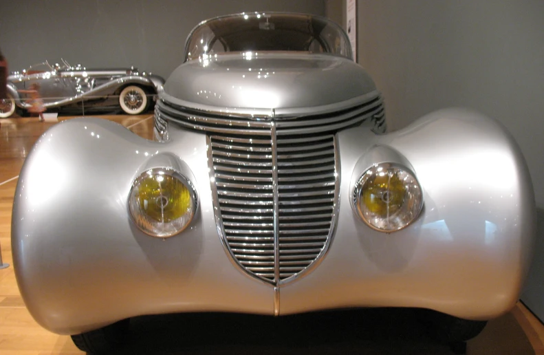 a large shiny silver car on display at a museum