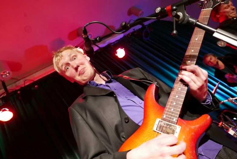 a man standing and playing guitar at an event