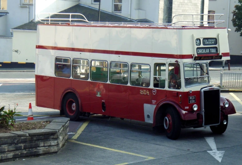 a red and white double decker bus traveling down the street