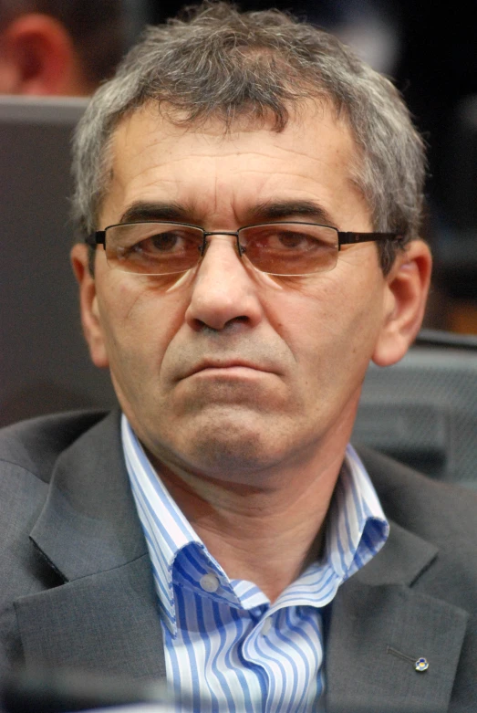 an older man with glasses is sitting in a chair