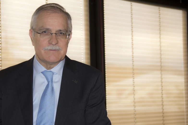 an older man wearing glasses and a blue tie