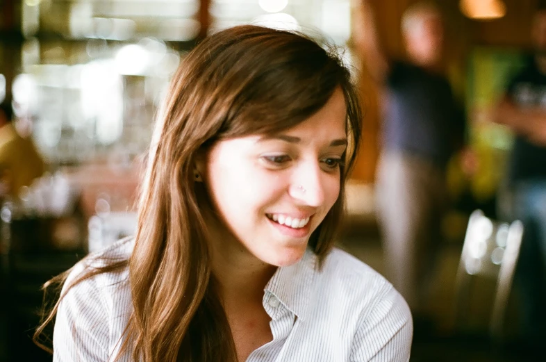 young woman in business casual attire looking down while talking on her cell phone