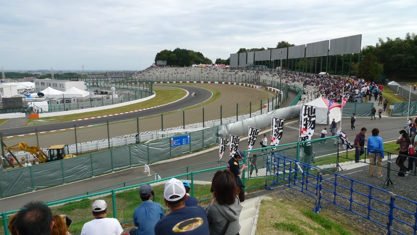 a group of people standing around a motorcycle track