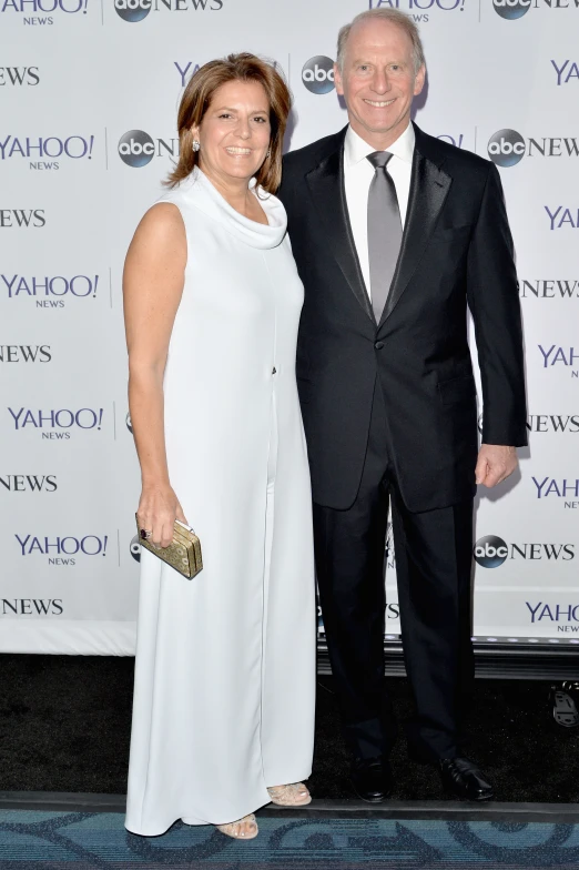 two people in suits and one wearing white on a blue carpet