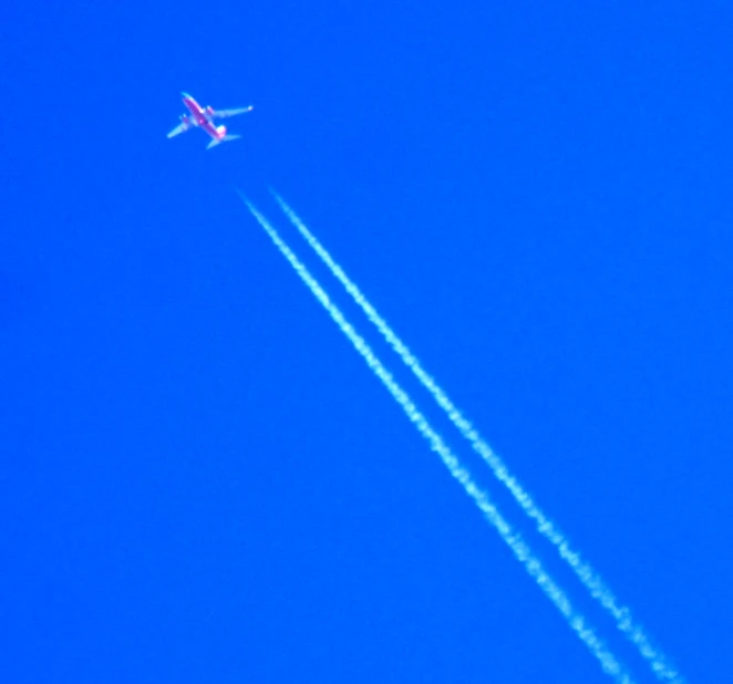 a jet is flying in the sky with an air strip passing behind it
