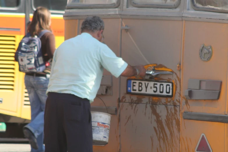 a man is washing the side of an old bus