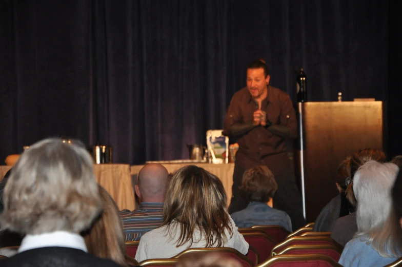 a man standing at the front of a room with people watching