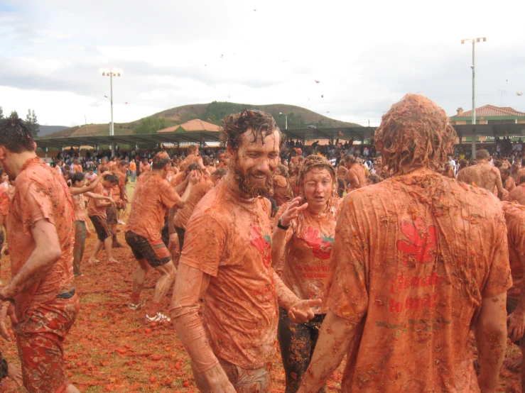 some people covered in mud and colored clothes are dancing around