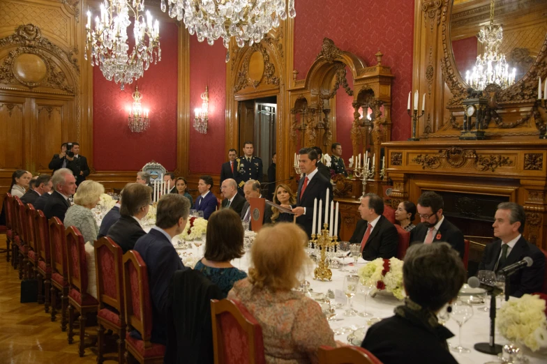 an elegant dining room is packed with people seated at long tables