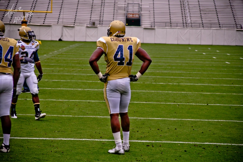 two opposing football players on the field at an empty stadium