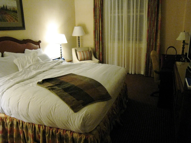 a bedroom with white linens and pillows that has a painting above the bed