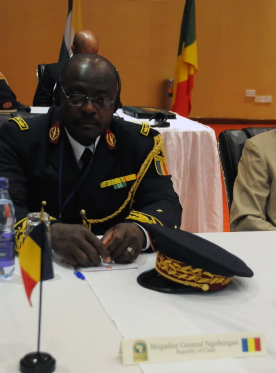 a military man in uniform sits at a table next to an empty table
