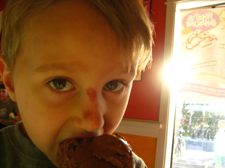 a  is licking his chocolate donut with his mouth