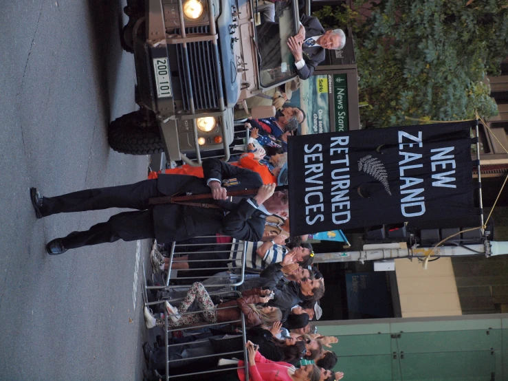 a man is holding a sign that says new zealand in front of a group of people