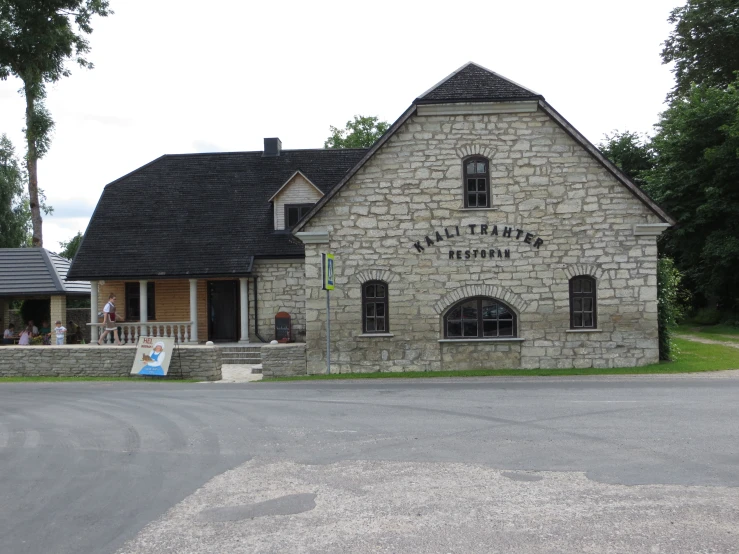 a grey house with black roof and stone walls and windows