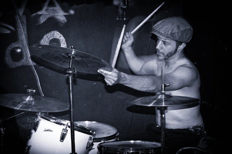 a shirtless man is playing drums in a drum kit