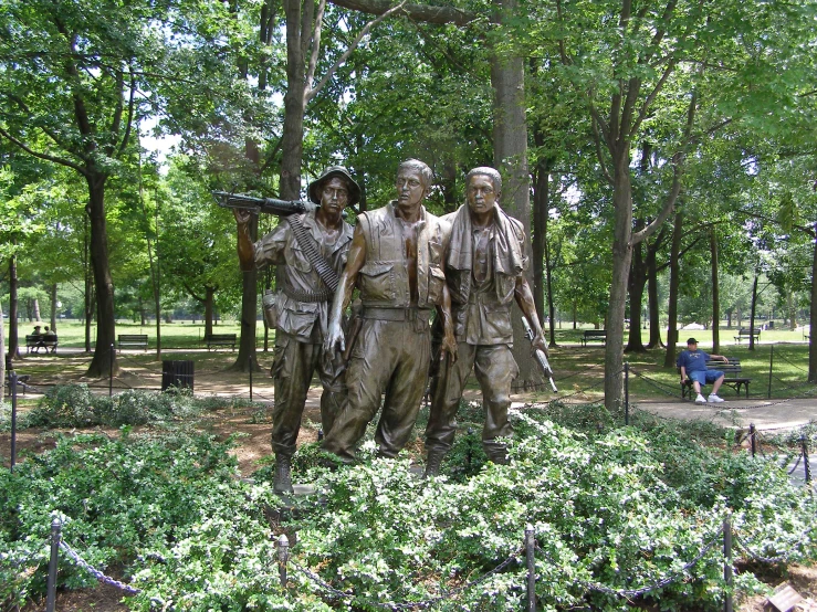 a couple of men stand next to some statues