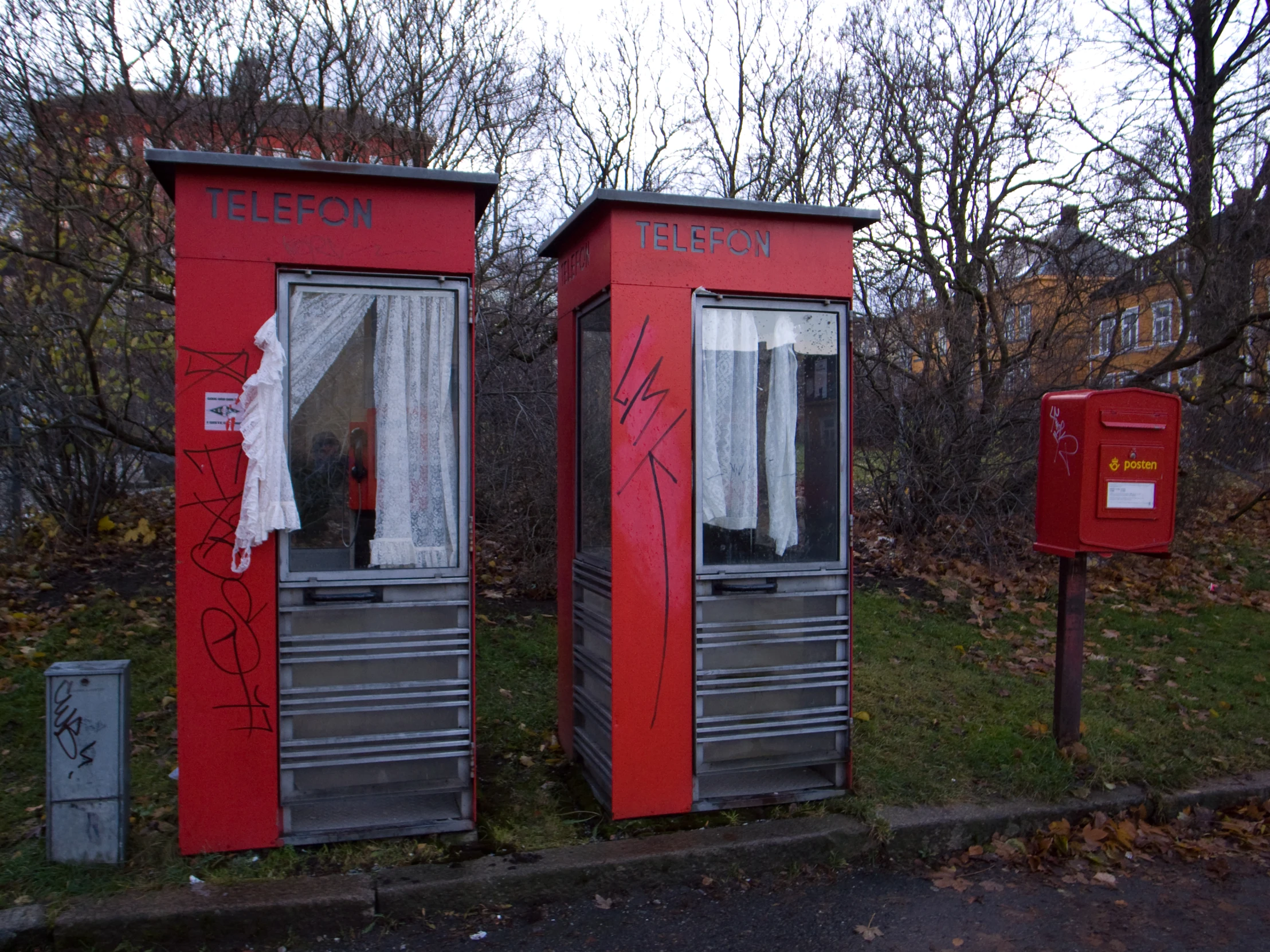 some red out houses near the street with graffiti on them