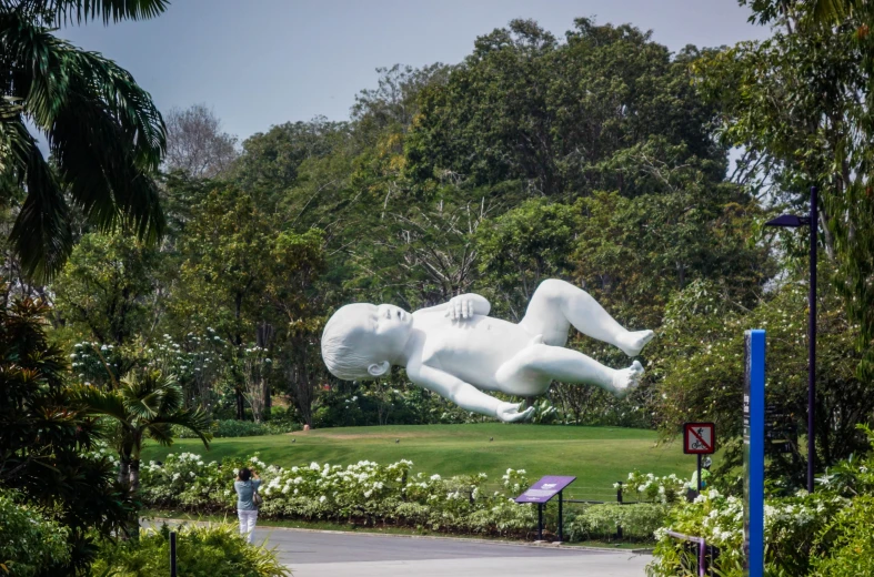 a very big white sculpture sitting on top of a lush green park