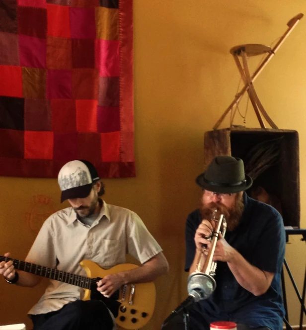 two young men playing instruments in front of a window