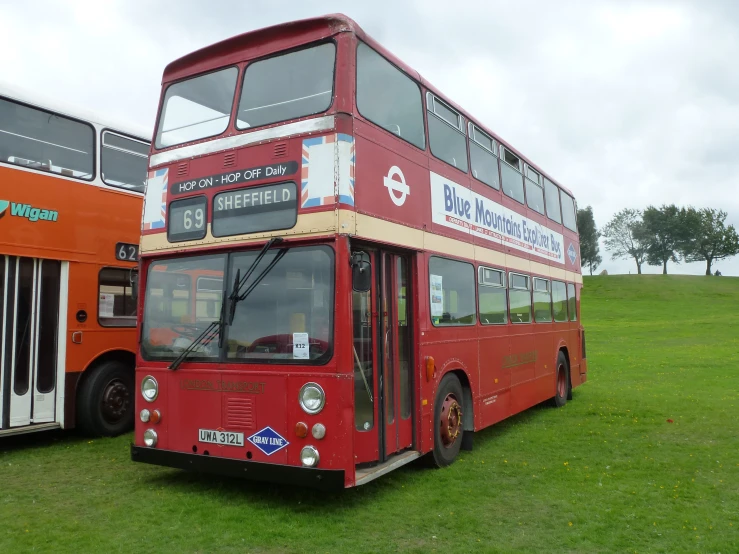 a double decker bus parked next to a red bus