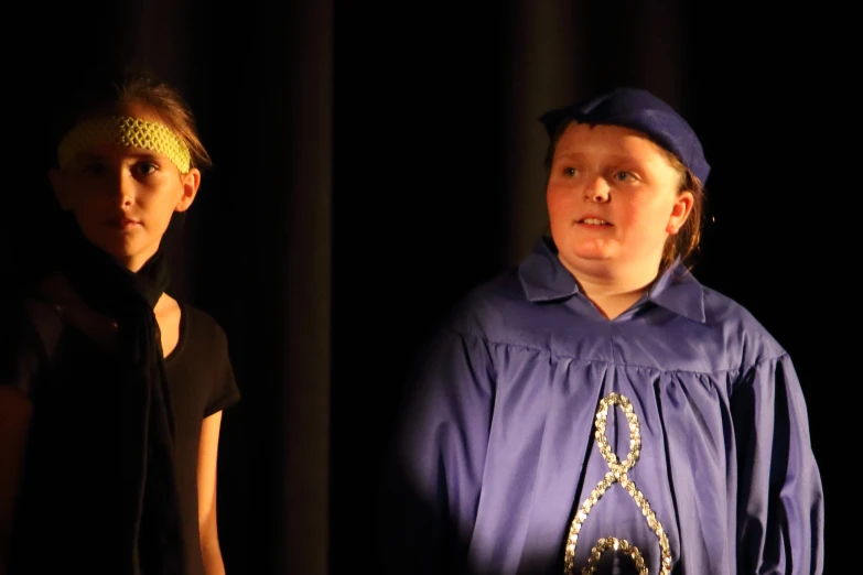 a boy and girl standing together in front of a curtain