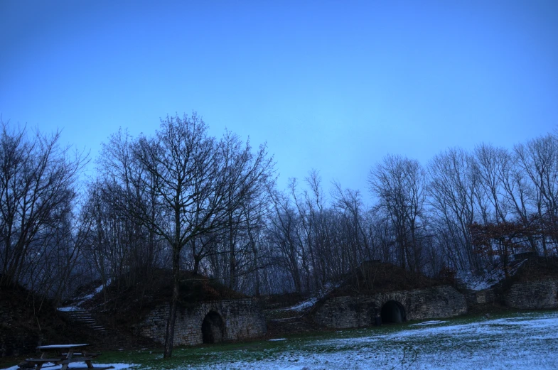 an area with snowy field and trees with benches around it