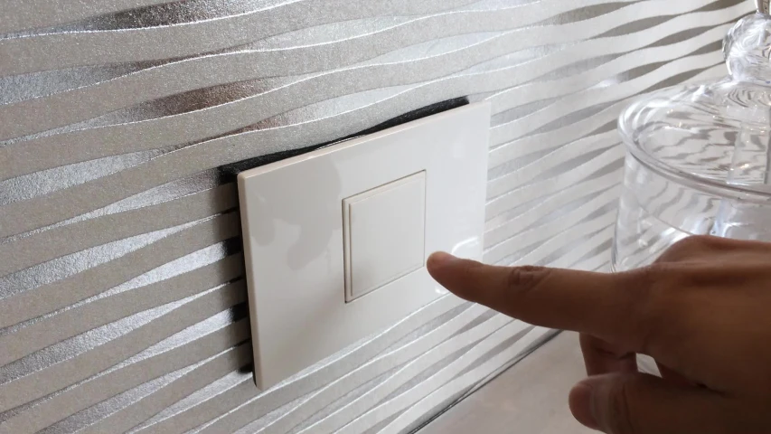 a hand points at a light switch that has been installed in a bedroom