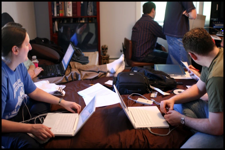 two people sitting on a bed with laptops