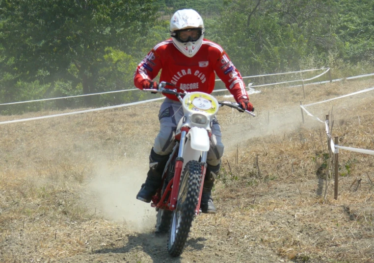 person in red shirt and helmet riding a dirt bike