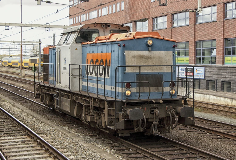 a train sits on tracks in front of a brick building