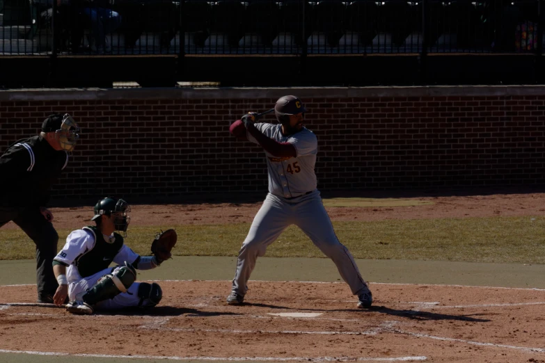 a baseball player swinging at a ball while the catcher prepares to catch it