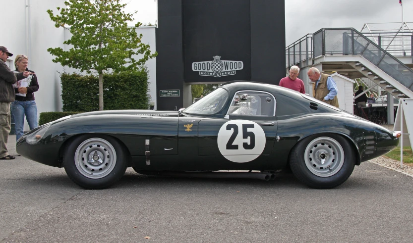 an antique sports car parked near a group of people