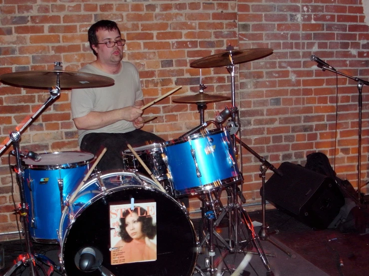 a person on a stage playing drums in front of a brick wall