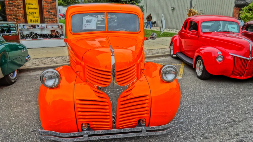 a classic orange car with a matching orange truck in the background