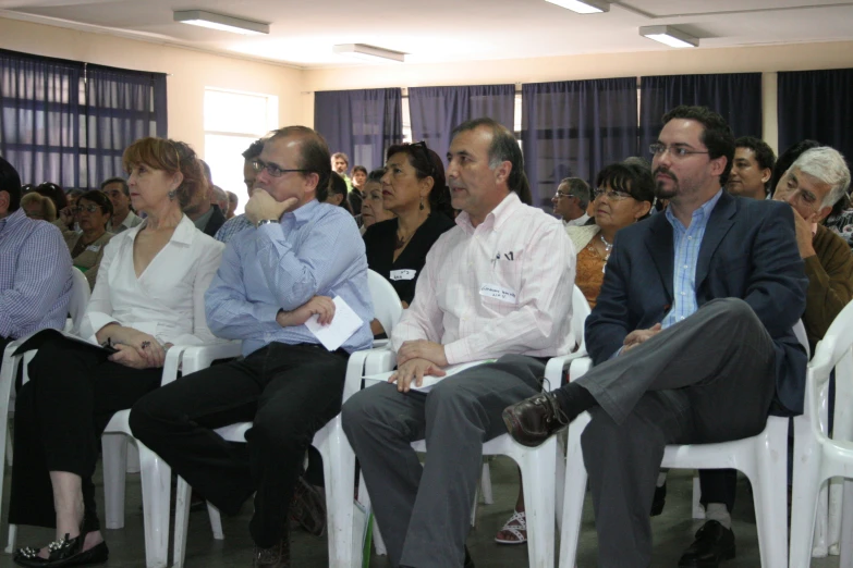 many people are in a room with one man sitting on a chair