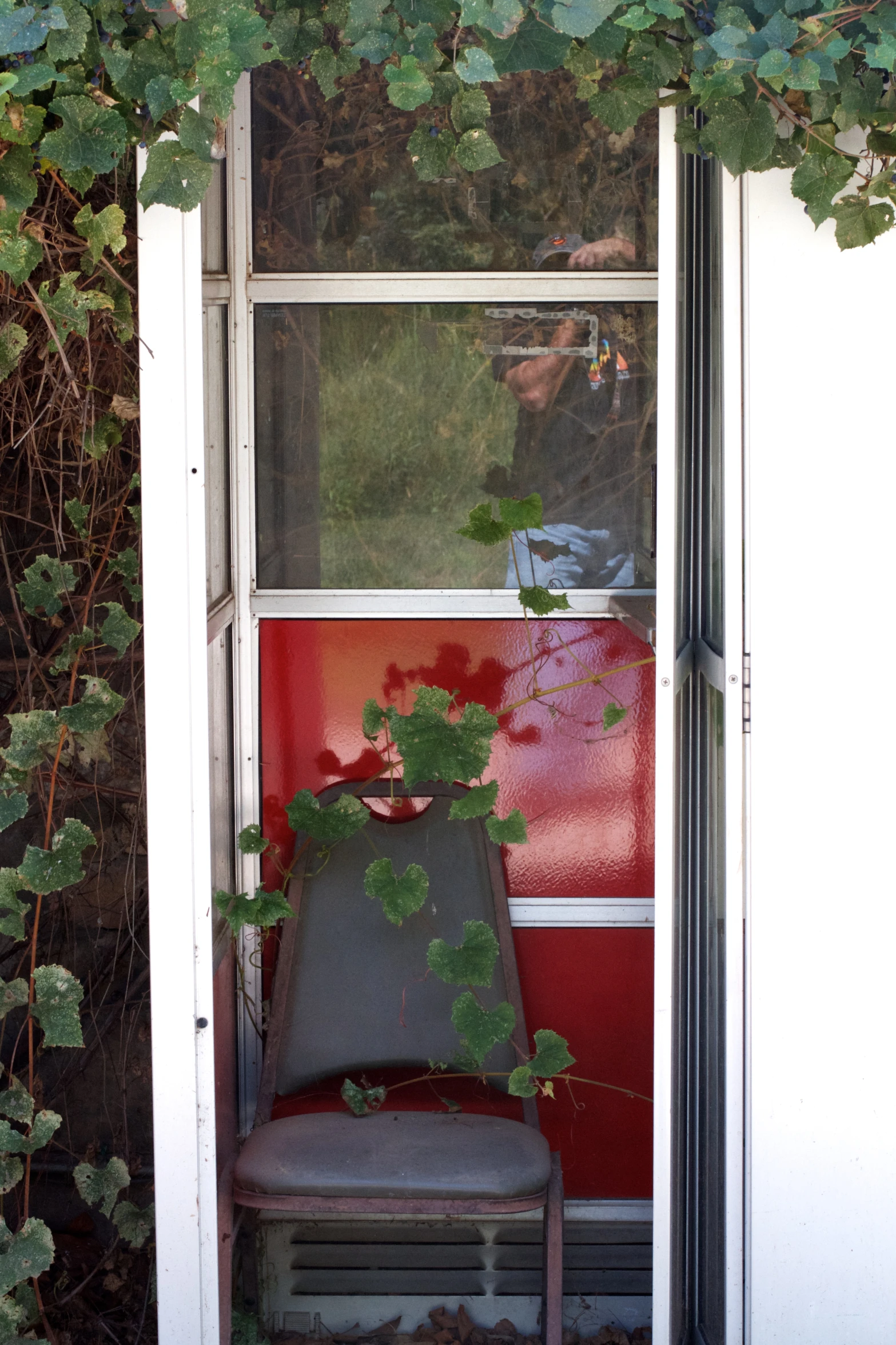 a gray chair outside in front of a red wall