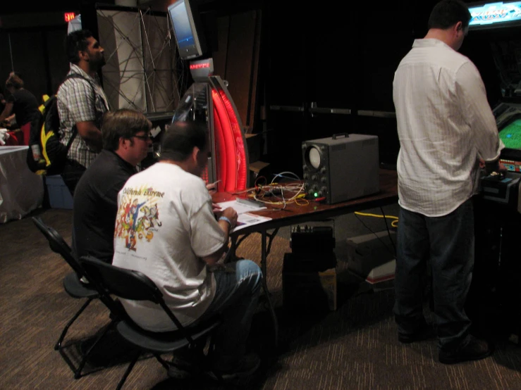 two men in front of a table with a projector and television