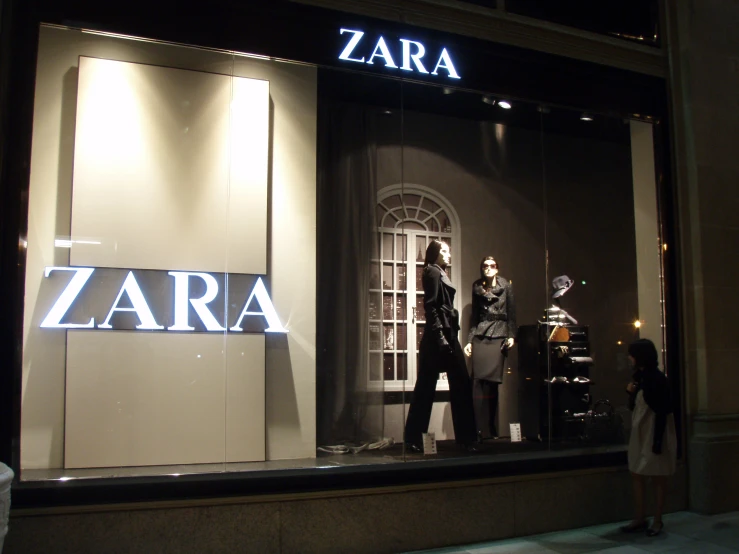 a woman in black and white clothes walking by a window