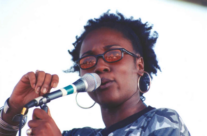 a woman in glasses is singing into a microphone