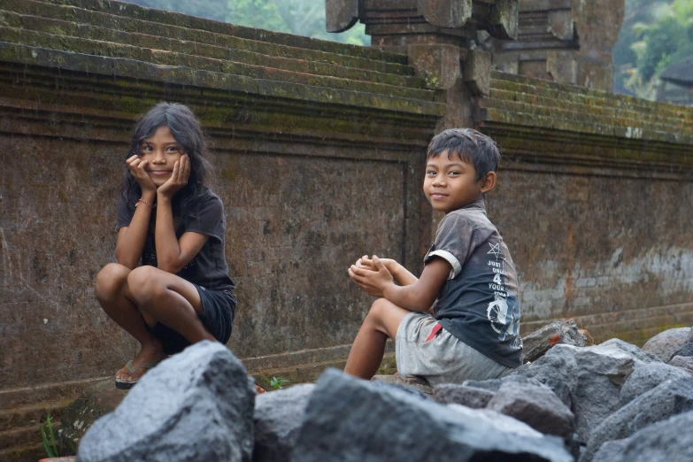 two children in the rain sitting on the ground