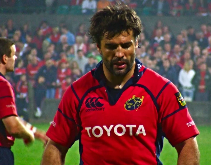 a man is in red jersey holding a black soccer ball