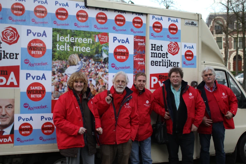 group of men in red jackets standing next to the front of a truck