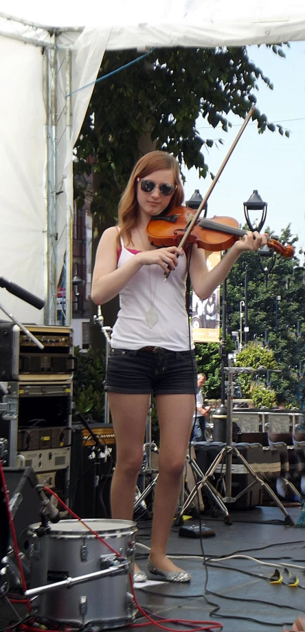 woman in striped shorts playing violin while standing on stage