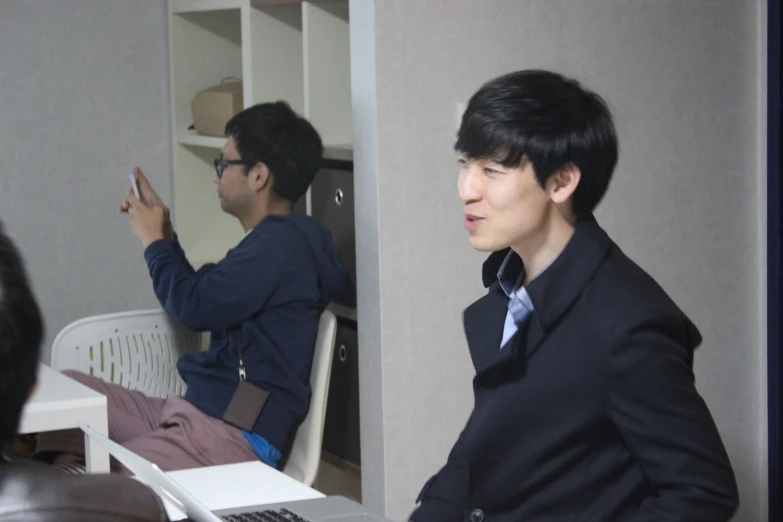 a man with black hair sitting in front of a laptop computer